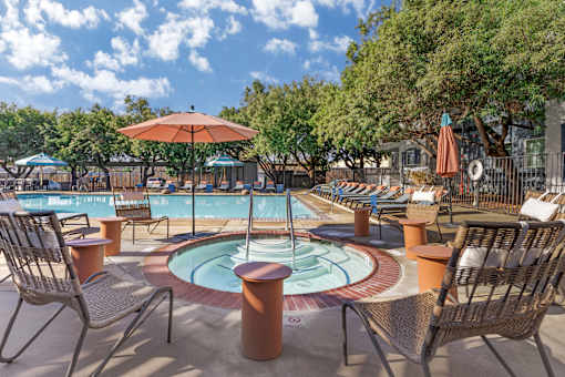 A pool area with chairs and umbrellas.