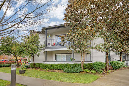 A grey two-story apartment building with a balcony on the second floor.