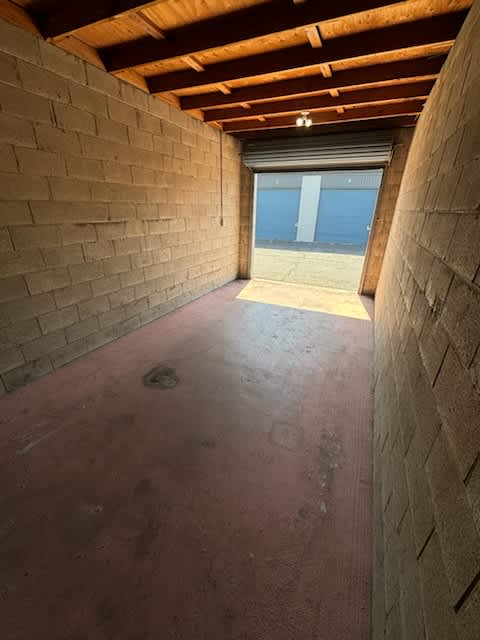 Spacious storage unit with sturdy cinder block walls, cement floor, and roll-up door for easy access. It is perfect for secure storage of personal items or inventory.