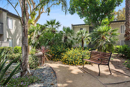 A bench sits in the middle of a garden at Twenty 2 Eleven Apartment Homes