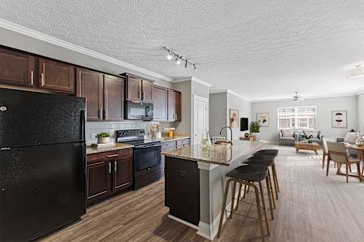 A modern kitchen with dark wood cabinets and a black refrigerator.