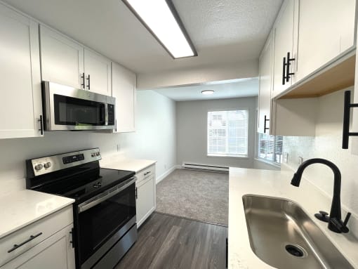 an empty kitchen with white cabinets and black appliances and a sink