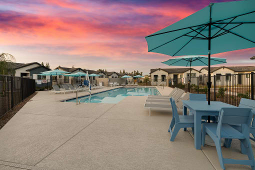 a swimming pool with blue tables and chairs and umbrellas at Villas on Ash, Arizona  