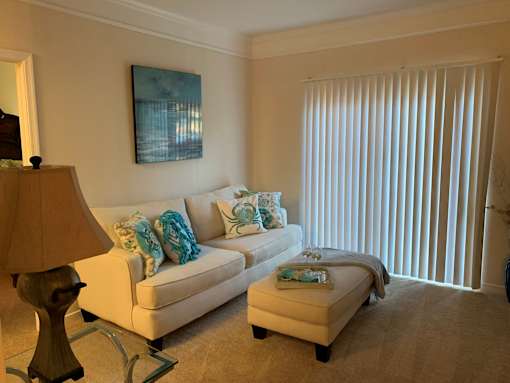 A living room with a white couch and a painting on the wall.