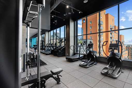 A gym with treadmills, weights, and a view of a cityscape at Link Apartments® QPN, Long Island City, New York