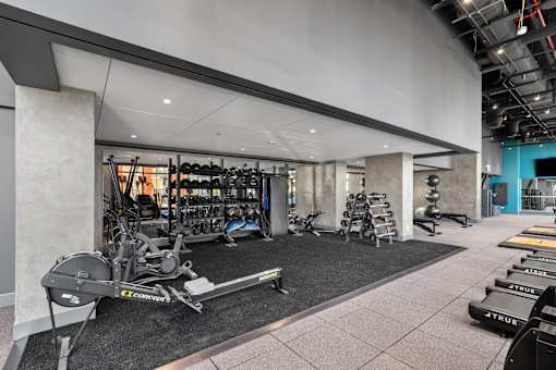 A gym with a variety of equipment including weights and cardio machines at Link Apartments® QPN, Long Island City, New York
