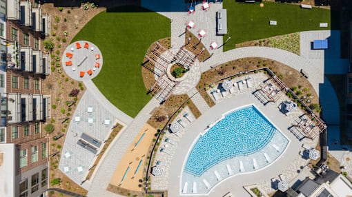 Beautiful drone shot of courtyard with pool, grills, and firepit at Link Apartments® Linden in Chapel Hill