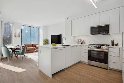 A modern kitchen with white cabinets and a wooden floor.