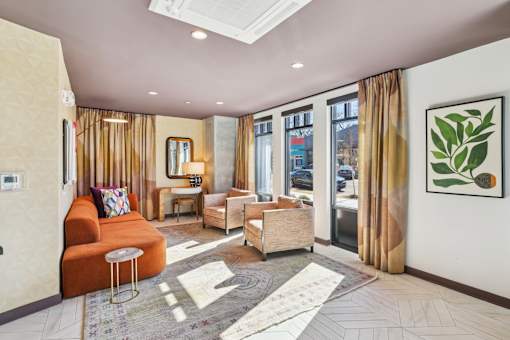 a living room with a orange couch and chairs and a window at Link Apartments® Broad Ave, Memphis, Tennessee