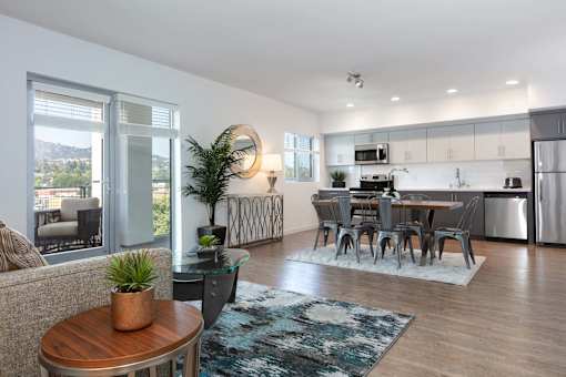 A modern living room with a dining area and kitchen in the background.