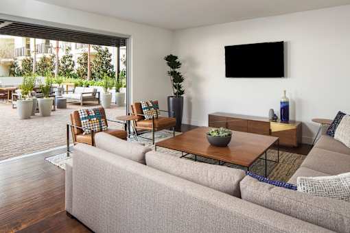 A living room with a grey couch, a wooden coffee table, and a flat screen TV mounted on the wall.