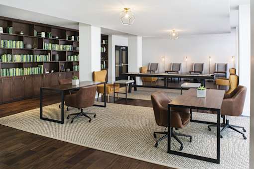 A room with a long table and chairs, a bookshelf, and a couch.