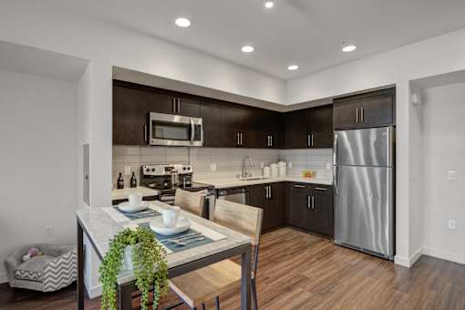 A modern kitchen with dark brown cabinets and stainless steel appliances.