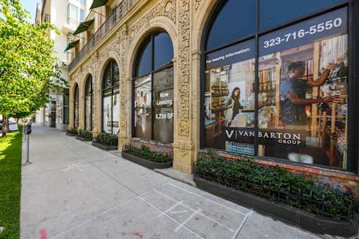 A sidewalk in front of a building with a large window advertising the Van Barton Group.