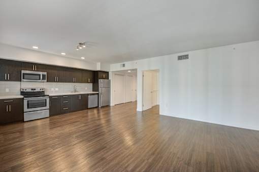 A kitchen with dark wood floors and white walls.