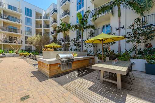 A patio with a table and chairs and a grill.