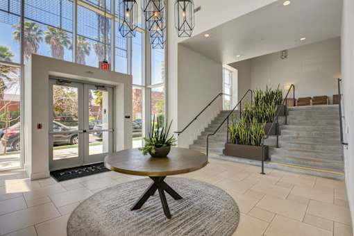 A round table with a plant on it is in the middle of a hallway.
