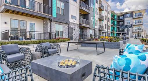 A patio with a fire pit and chairs.