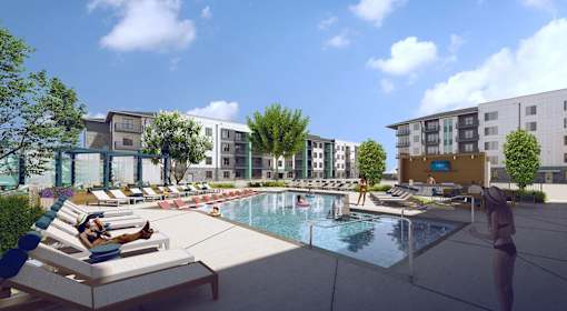 A pool area with lounge chairs and a person standing by the pool.