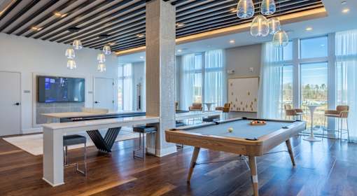 A billiard table is in the middle of a room with a television and chairs.