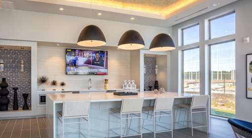 A modern kitchen with a bar area and a television mounted on the wall.