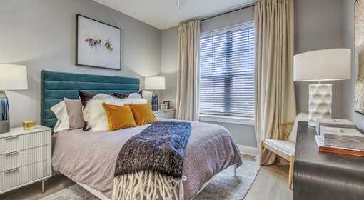 A bedroom with a bed, nightstand, and window.