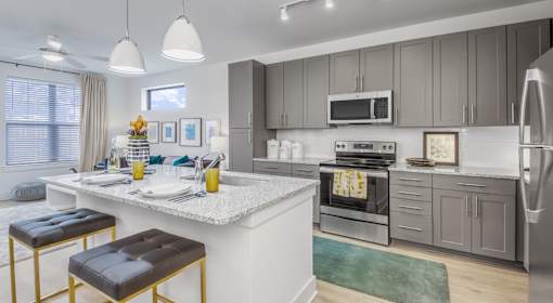 A modern kitchen with a white countertop and stainless steel appliances.