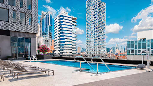 A swimming pool on a rooftop with a city skyline in the background.