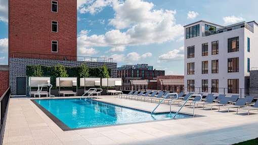 A pool with lounge chairs and a building in the background.