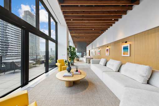 A modern room with a large window overlooking the city at Link Apartments® QPN, Long Island City, New York