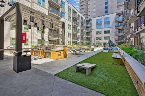 an outdoor lounge area with a picnic table and a grill in an apartment building at Link Apartments® 4th Street, Winston-Salem, North Carolina