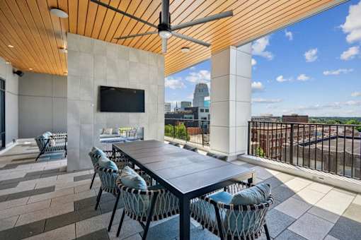a patio with a table and chairs and a tv at Link Apartments® 4th Street, Winston-Salem, North Carolina