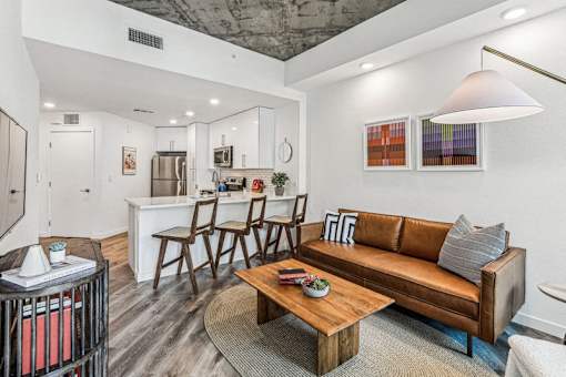 a living room with a couch and a coffee table in front of a kitchen at Link Apartments® Four 12, Oakland