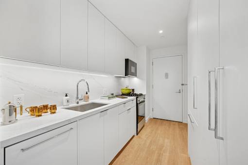 A kitchen with white cabinets and a wooden floor.at Link Apartments® QPN, Long Island City, 11101