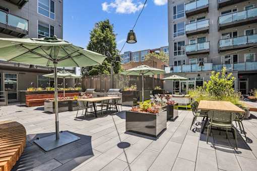 a patio with tables and chairs and umbrellas at Link Apartments® Four 12, Oakland, 94607