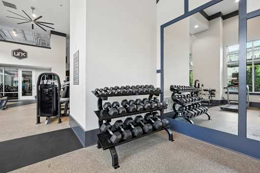 Fitness center with dumbbell rack and mirrors at Link ® West End Apartments, Greenville