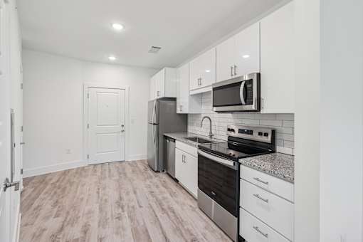 A kitchen with white cabinets and a black stove top oven at Link Apartments® CYKEL Apartments, North Carolina, 28208