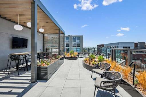 the settlement rooftop patio with tables and chairs and a tv at Link Apartments® Four 12, Oakland, CA