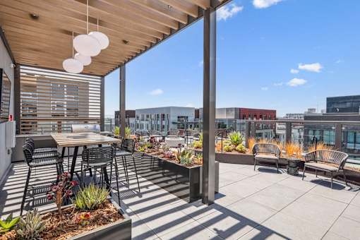 a patio with tables and chairs on the roof of a building at Link Apartments® Four 12, California, 94607