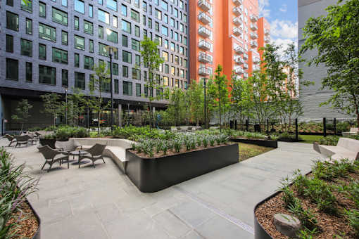 A modern courtyard with a planter box and chairs at Link Apartments® QPN, Long Island City, New York