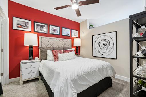 Bedroom with red accent wall and ceiling fan at Link ® West End Apartments, Greenville, SC