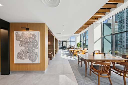 A long hallway with tables and chairs on either side at Link Apartments® QPN, Long Island City, New York