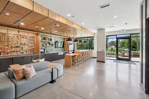 A modern kitchen with a grey couch and wooden cabinets at Link Apartments® CYKEL Apartments, Charlotte, North Carolina