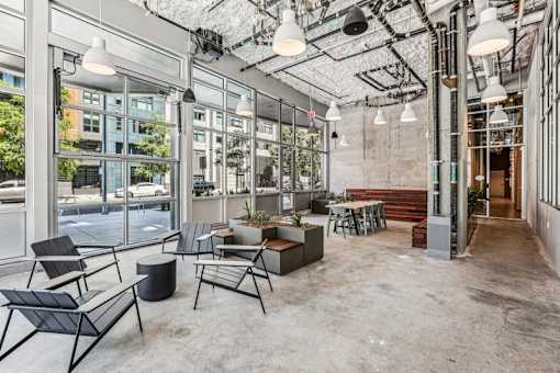 the lobby of a building with chairs and tables and large windows at Link Apartments® Four 12, California