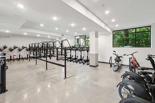 A gym with a row of exercise bikes and a row of treadmills at Link Apartments® CYKEL Apartments, Charlotte, NC