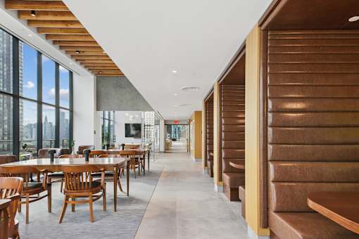 A long hallway with wooden benches on the right and tables on the left at Link Apartments® QPN, Long Island City, New York