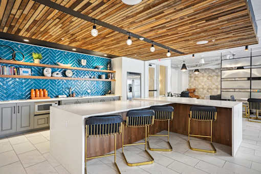 a kitchen with a counter and three chairs at Link Apartments® 4th Street, Winston-Salem