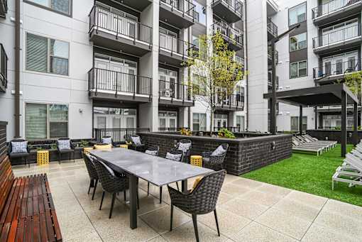 an outdoor patio with a table and chairs in front of an apartment building at Link Apartments® Mint Street, Charlotte, NC, 28203