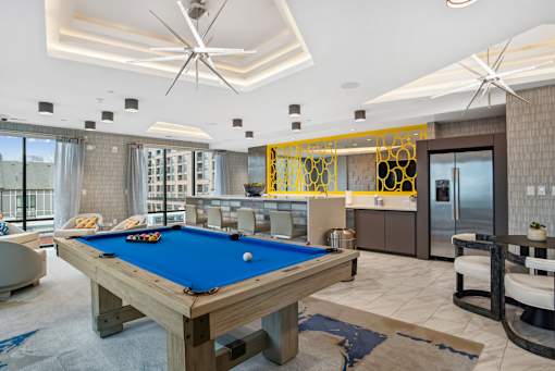 a pool table in a living room with a bar and a kitchen at Link Apartments® Mint Street, Charlotte, NC, 28203