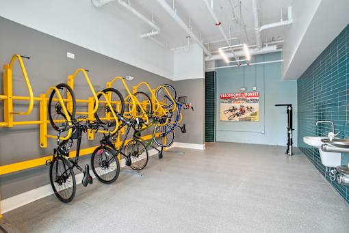 a room with several bikes hanging on a wall and a bathroom with sinks at Link Apartments® Mint Street, North Carolina, 28203
